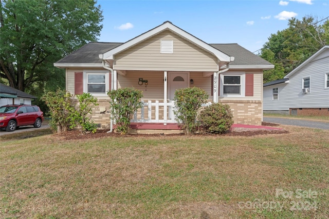 bungalow featuring a front yard, cooling unit, and covered porch