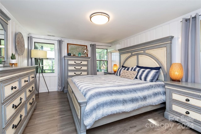 bedroom with multiple windows, dark hardwood / wood-style flooring, and ornamental molding