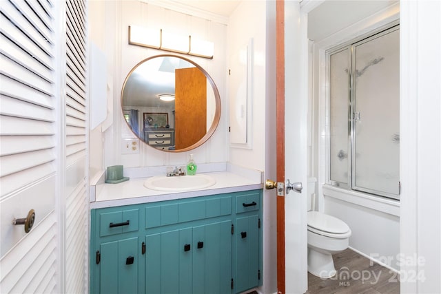 full bathroom with vanity, bath / shower combo with glass door, toilet, ornamental molding, and hardwood / wood-style flooring