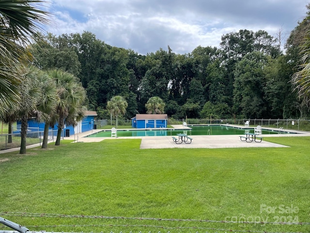 view of community with a water view, a yard, a pool, and an outdoor structure