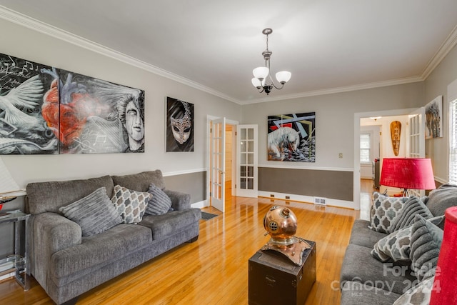 living room with wood-type flooring, ornamental molding, and a chandelier