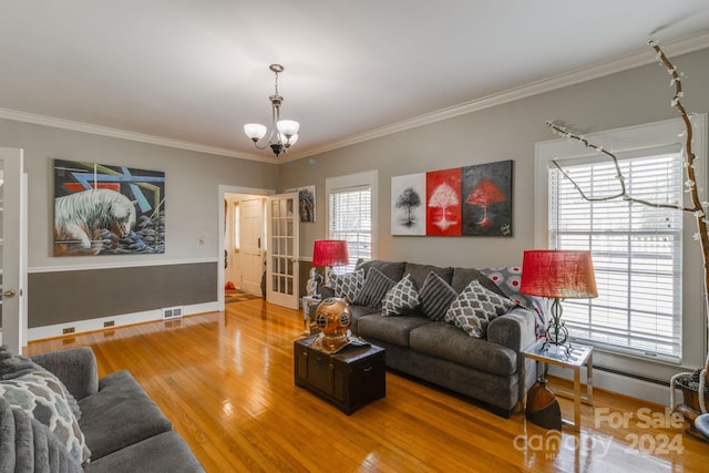 living room with a notable chandelier, crown molding, hardwood / wood-style floors, and a wealth of natural light