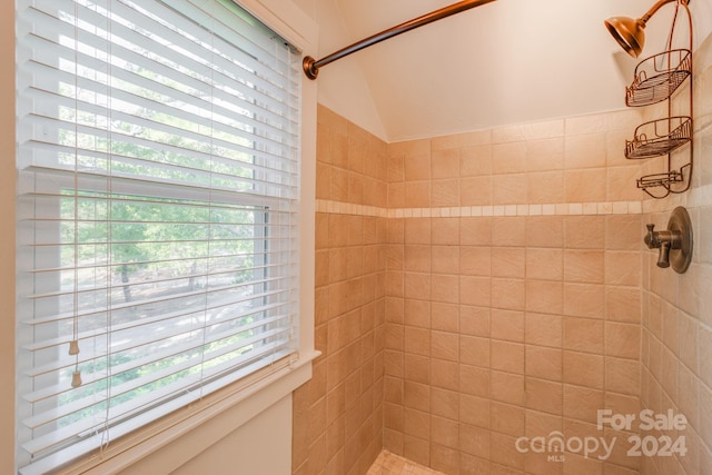 bathroom featuring tiled shower and lofted ceiling