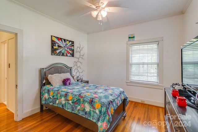 bedroom with wood-type flooring, ceiling fan, and crown molding