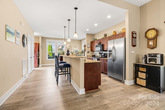 kitchen with pendant lighting, an island with sink, light wood-type flooring, stainless steel appliances, and light stone countertops