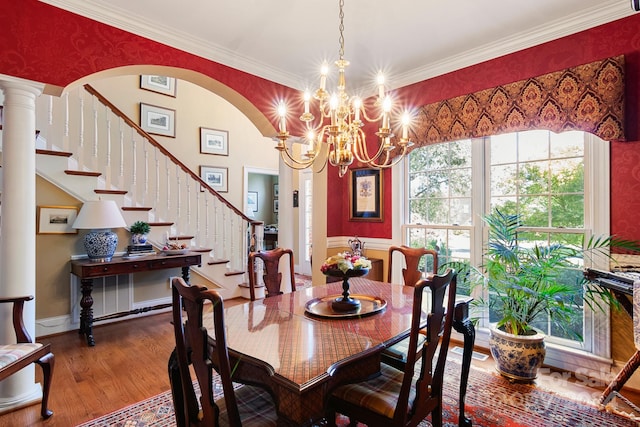 dining space featuring a healthy amount of sunlight, hardwood / wood-style floors, a chandelier, and decorative columns