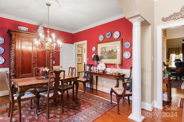 dining room with crown molding, wood-type flooring, ornate columns, and a notable chandelier