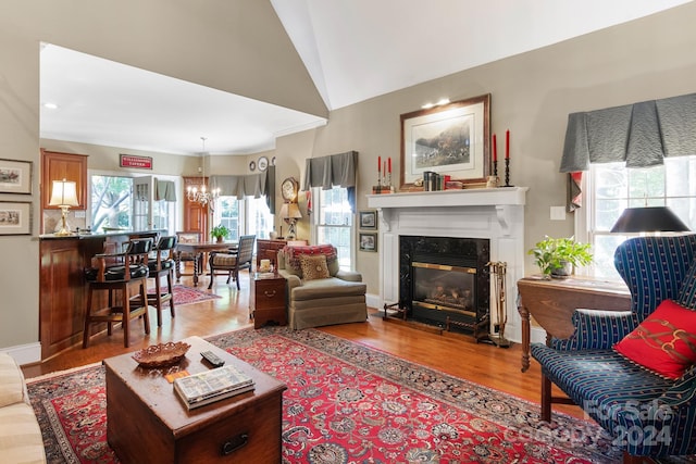 living room featuring a fireplace, vaulted ceiling, wood-type flooring, and a notable chandelier