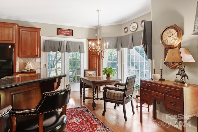 dining space featuring crown molding, a chandelier, and light hardwood / wood-style flooring