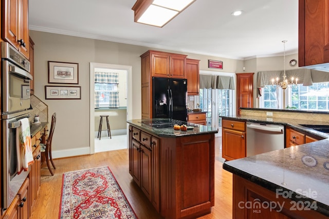 kitchen with light wood-type flooring, black appliances, a kitchen island, an inviting chandelier, and hanging light fixtures