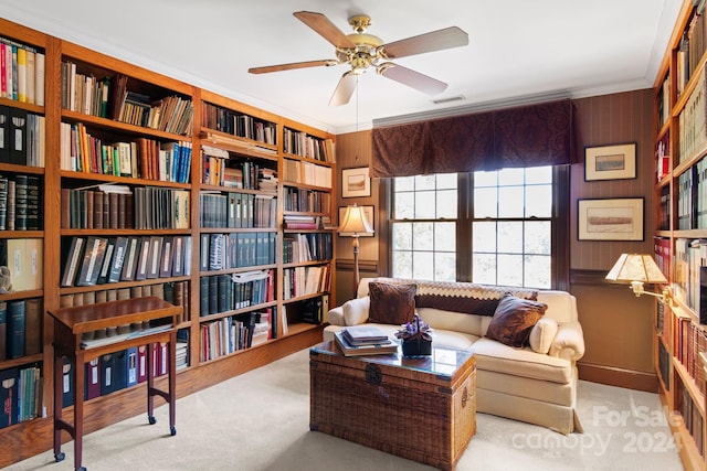 sitting room with ceiling fan, light colored carpet, and crown molding