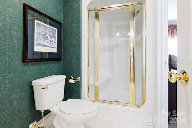 bathroom featuring toilet, a shower with shower door, and tile patterned flooring