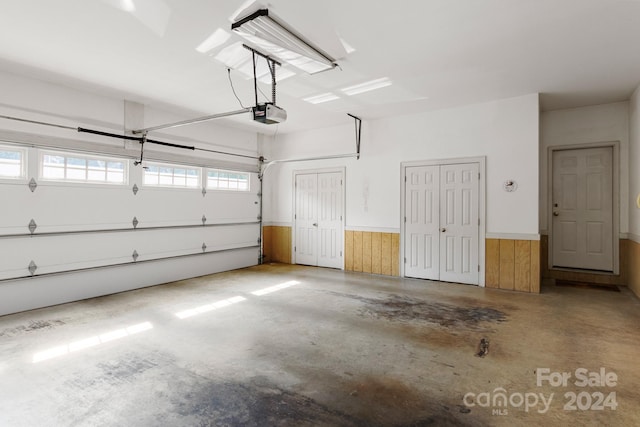 garage featuring a garage door opener and wooden walls