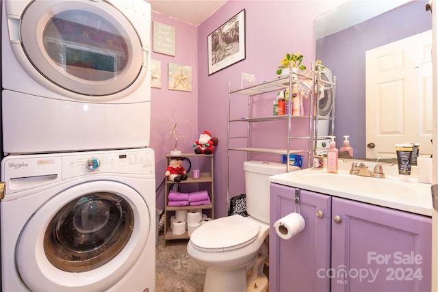 bathroom with vanity, toilet, and stacked washer and dryer