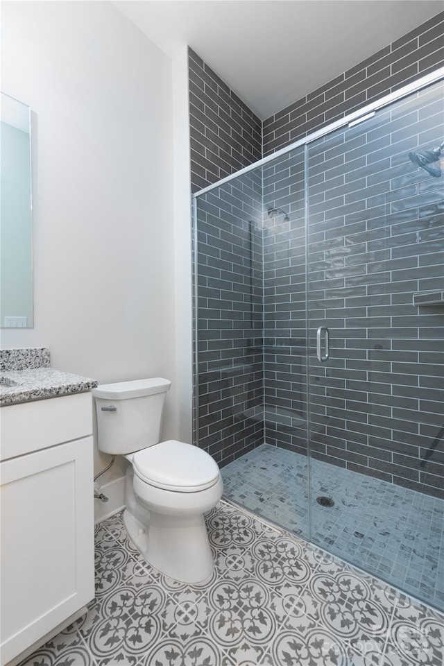 bathroom featuring vanity, toilet, and a shower with door