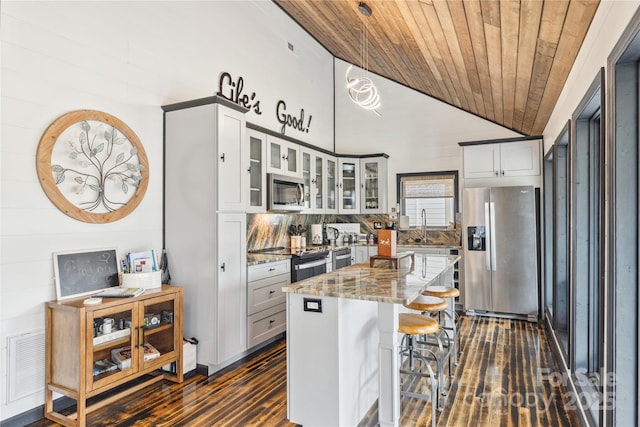 kitchen featuring appliances with stainless steel finishes, a center island, stone countertops, vaulted ceiling, and wooden ceiling