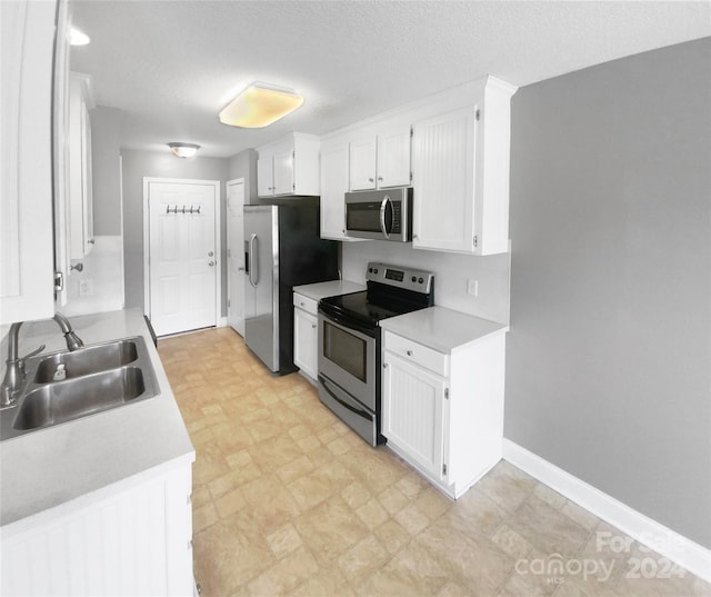 kitchen featuring a textured ceiling, sink, appliances with stainless steel finishes, and white cabinetry