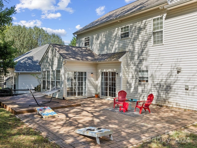 rear view of house with a wooden deck, a patio, and a fire pit