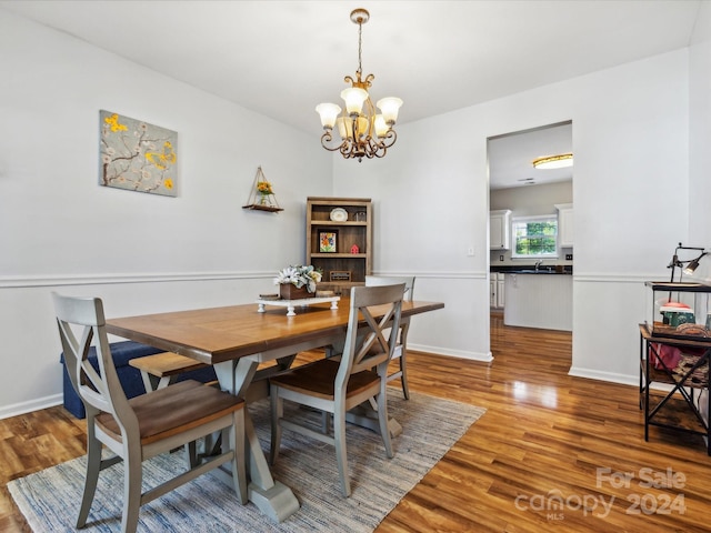 dining space with hardwood / wood-style flooring, sink, and a chandelier