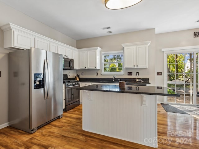 kitchen with hardwood / wood-style flooring, appliances with stainless steel finishes, plenty of natural light, and white cabinets