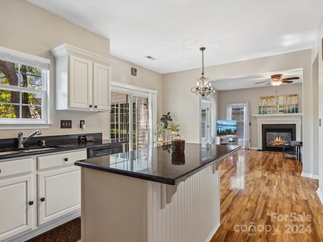 kitchen with a kitchen bar, light wood-type flooring, a center island, pendant lighting, and white cabinets