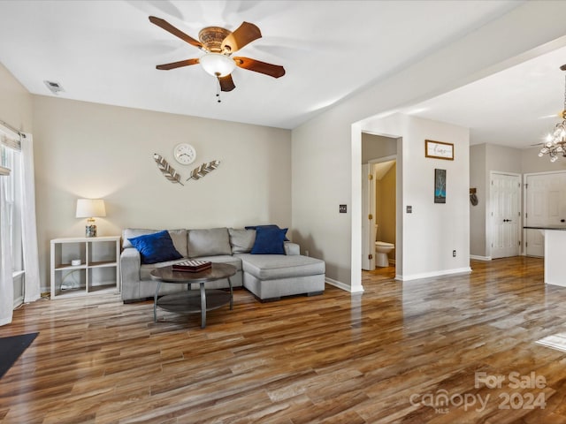 living room with hardwood / wood-style floors and ceiling fan with notable chandelier