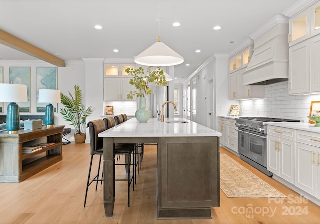 kitchen with white cabinets, custom exhaust hood, sink, double oven range, and light wood-type flooring