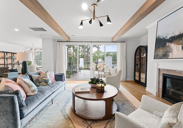 living room featuring light wood-type flooring, beamed ceiling, and plenty of natural light