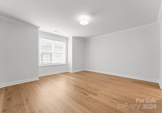 empty room featuring light hardwood / wood-style flooring and ornamental molding