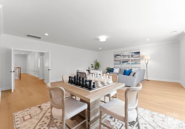 dining area with light wood-type flooring and crown molding