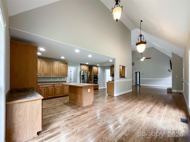 kitchen featuring hanging light fixtures, a center island, light hardwood / wood-style flooring, stainless steel fridge, and ceiling fan