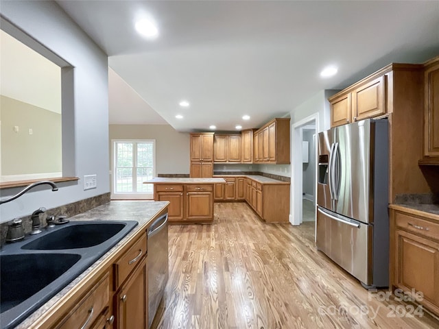 kitchen with stainless steel appliances, sink, and light hardwood / wood-style floors