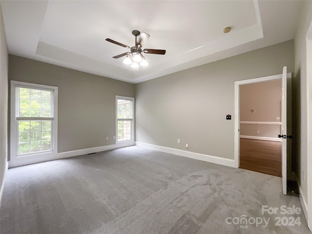 empty room featuring carpet flooring, ceiling fan, and a raised ceiling