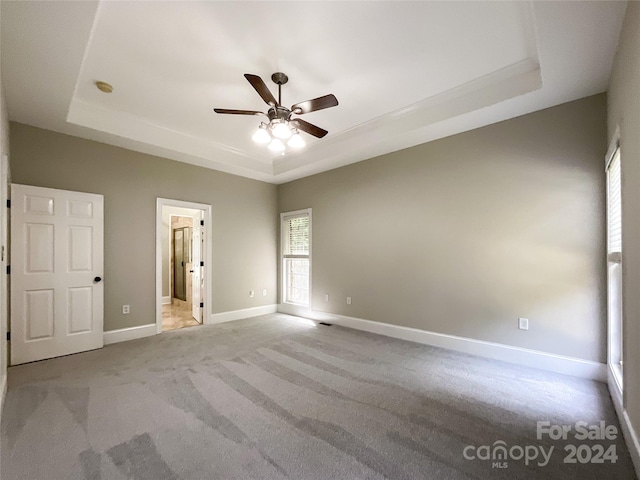 carpeted empty room featuring a raised ceiling and ceiling fan