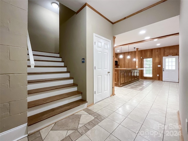 staircase featuring tile patterned flooring, crown molding, and wood walls