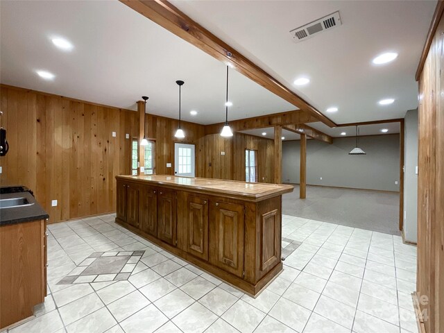 kitchen featuring light carpet, a kitchen island, wood walls, and hanging light fixtures