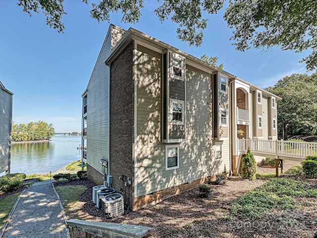 view of side of home featuring cooling unit and a water view