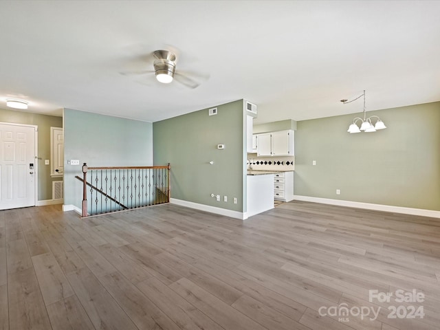 unfurnished room with ceiling fan with notable chandelier and light hardwood / wood-style floors