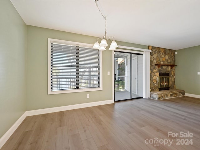 unfurnished living room featuring a fireplace, a chandelier, and hardwood / wood-style floors