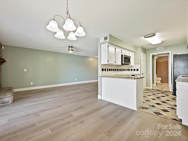 kitchen featuring white cabinets, hanging light fixtures, appliances with stainless steel finishes, ceiling fan with notable chandelier, and light hardwood / wood-style floors