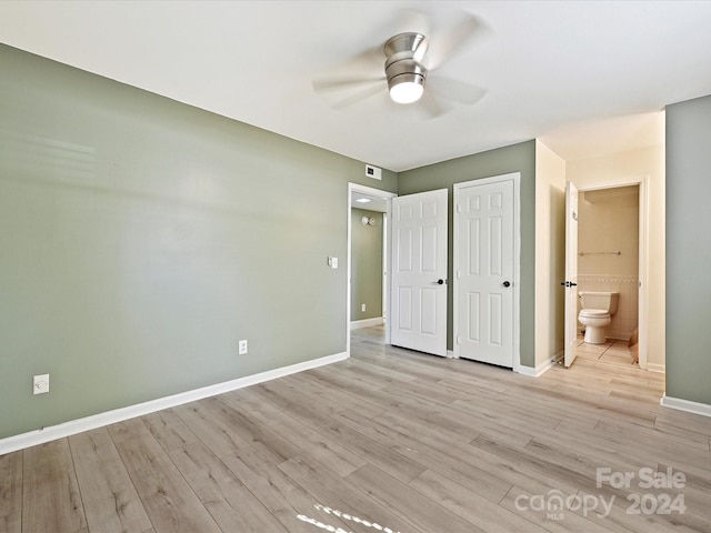 unfurnished bedroom with a closet, light wood-type flooring, ensuite bath, and ceiling fan