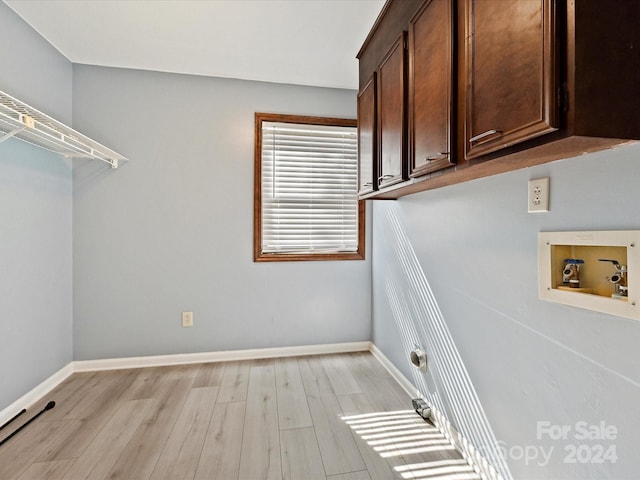 washroom featuring washer hookup, light hardwood / wood-style flooring, and cabinets