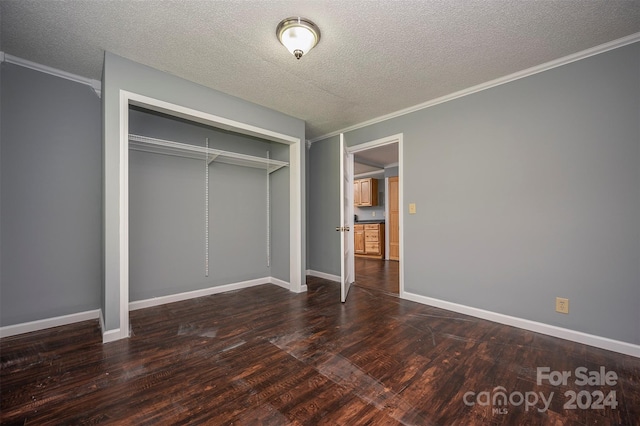 unfurnished bedroom featuring ornamental molding, a closet, a textured ceiling, and dark hardwood / wood-style floors