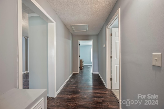 corridor with a textured ceiling and dark hardwood / wood-style floors