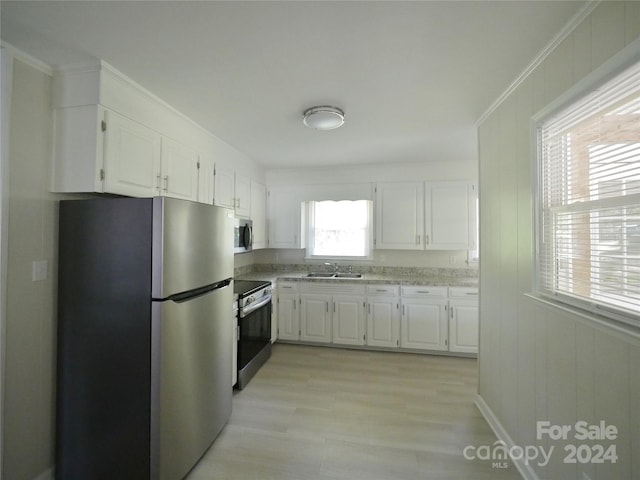 kitchen featuring light wood-type flooring, sink, white cabinets, appliances with stainless steel finishes, and ornamental molding