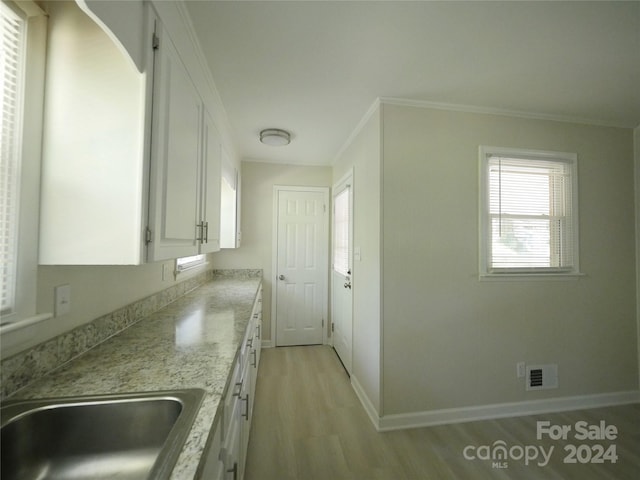 kitchen featuring light hardwood / wood-style floors, sink, white cabinetry, crown molding, and light stone countertops