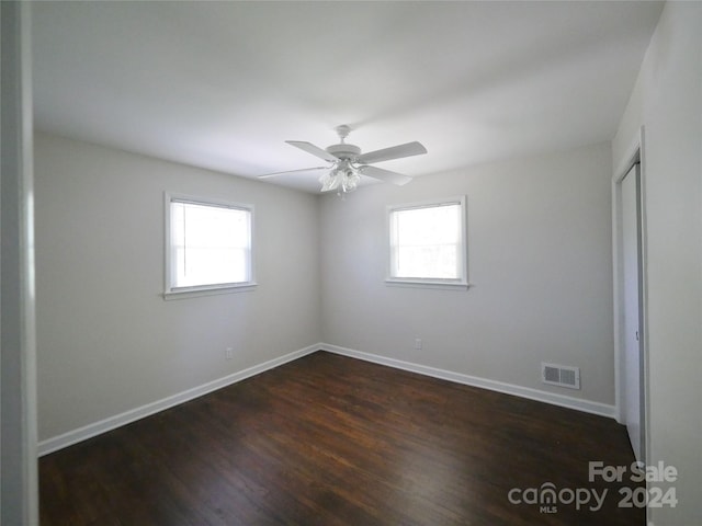 spare room featuring ceiling fan, plenty of natural light, and dark wood-type flooring