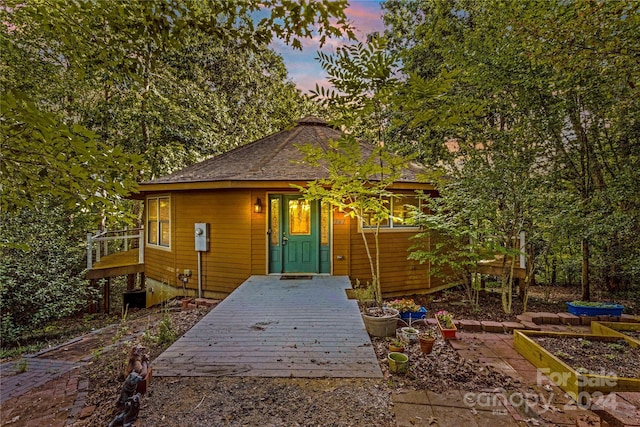 back of property at dusk with roof with shingles