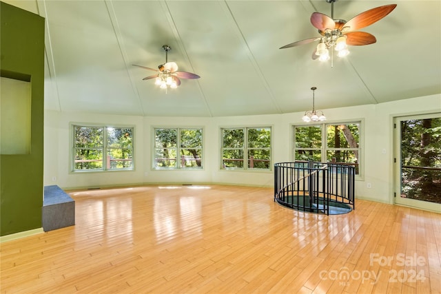 interior space featuring high vaulted ceiling, ceiling fan with notable chandelier, baseboards, and wood finished floors