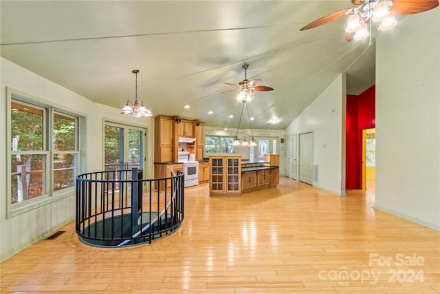 interior space featuring ceiling fan with notable chandelier, vaulted ceiling, and light hardwood / wood-style floors